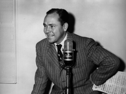 Johnny Mercer standing by a microphone.