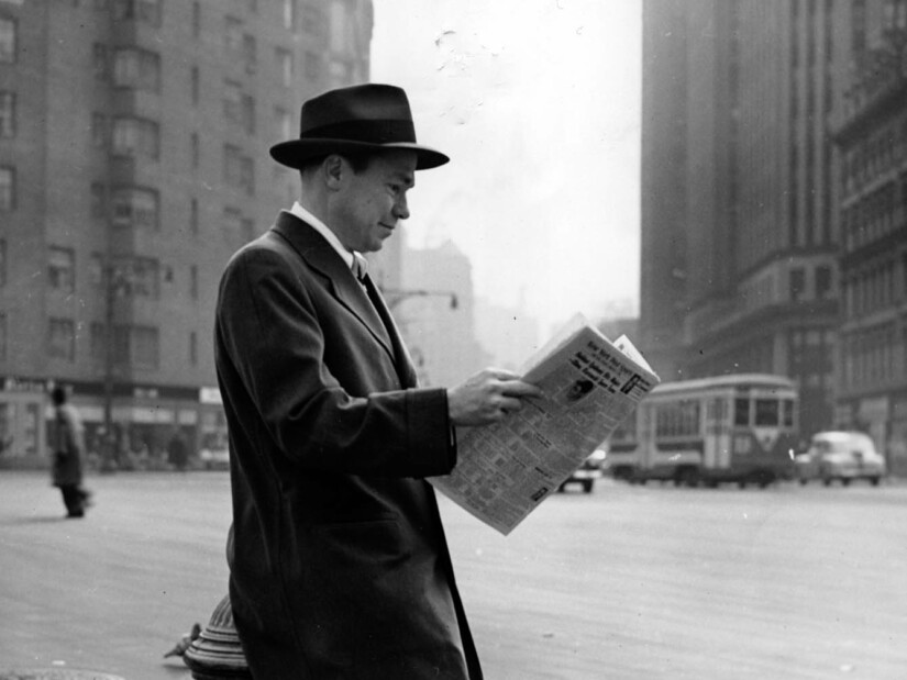 Johnny Mercer leaning against a fire hydrant reading a newspaper.